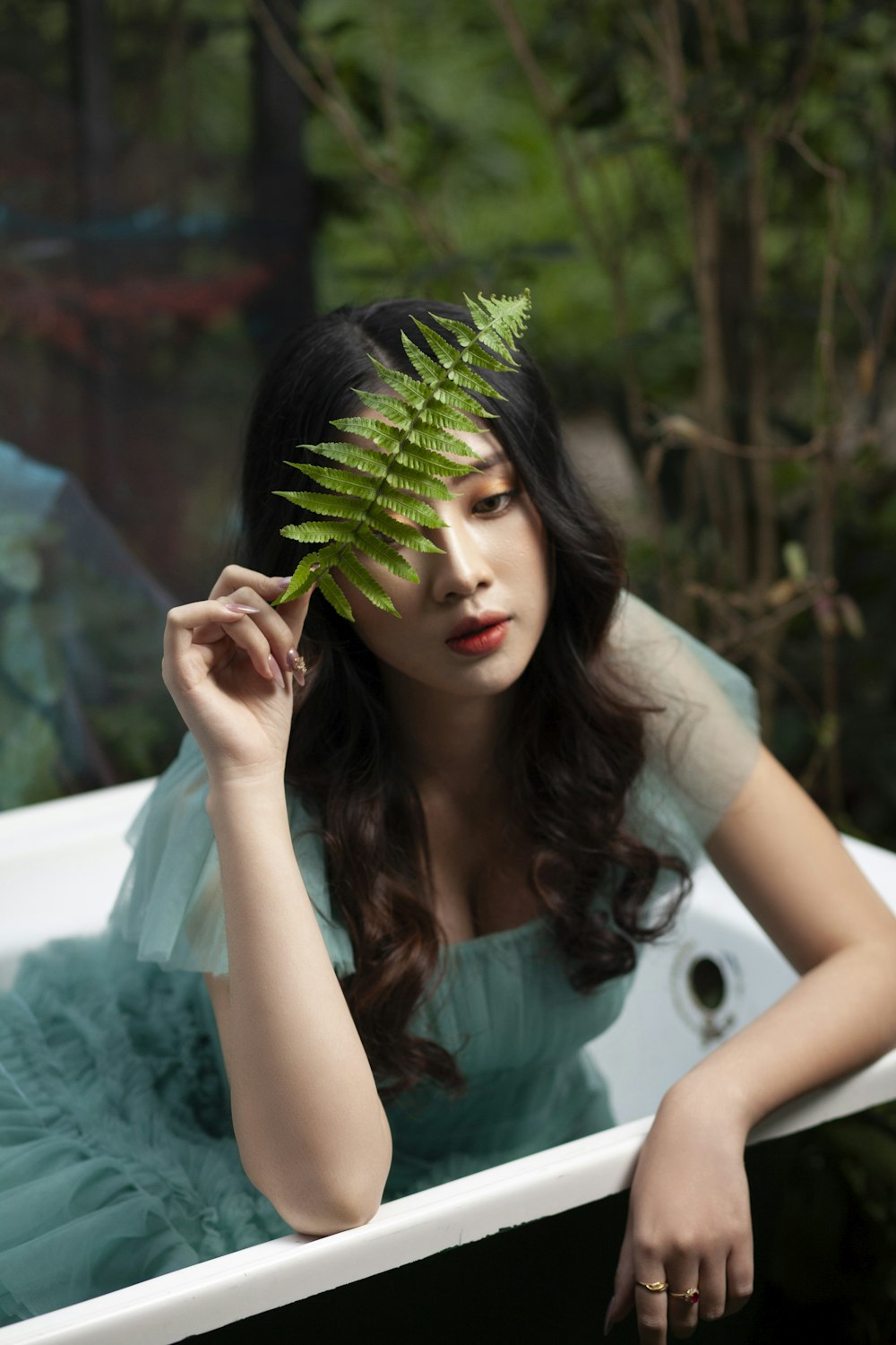 woman in teal dress holding green plant