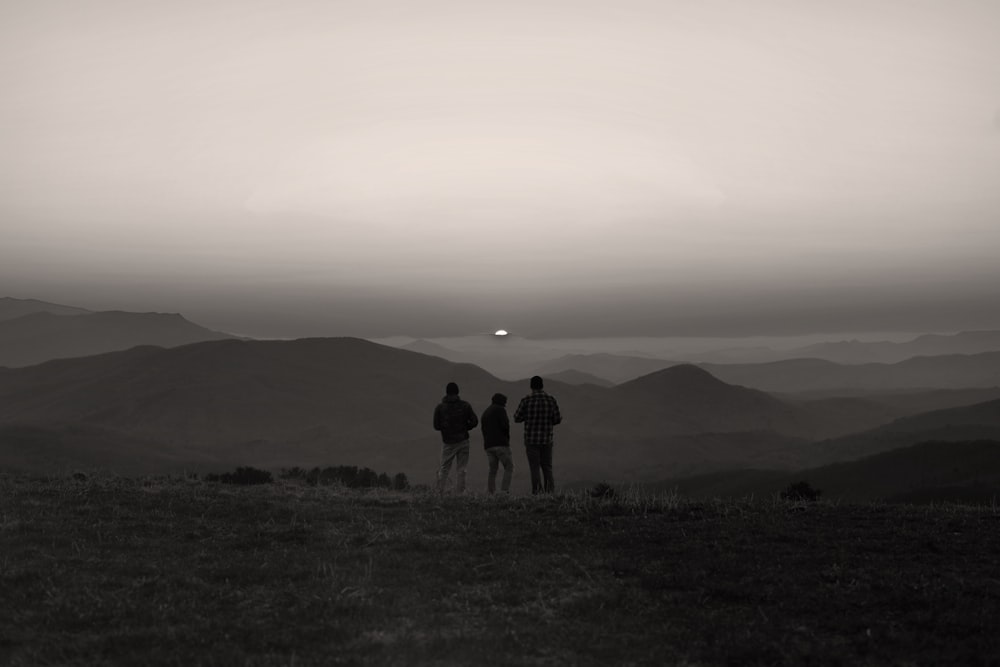 Silhouette de 3 personnes debout sur un champ d’herbe pendant la journée