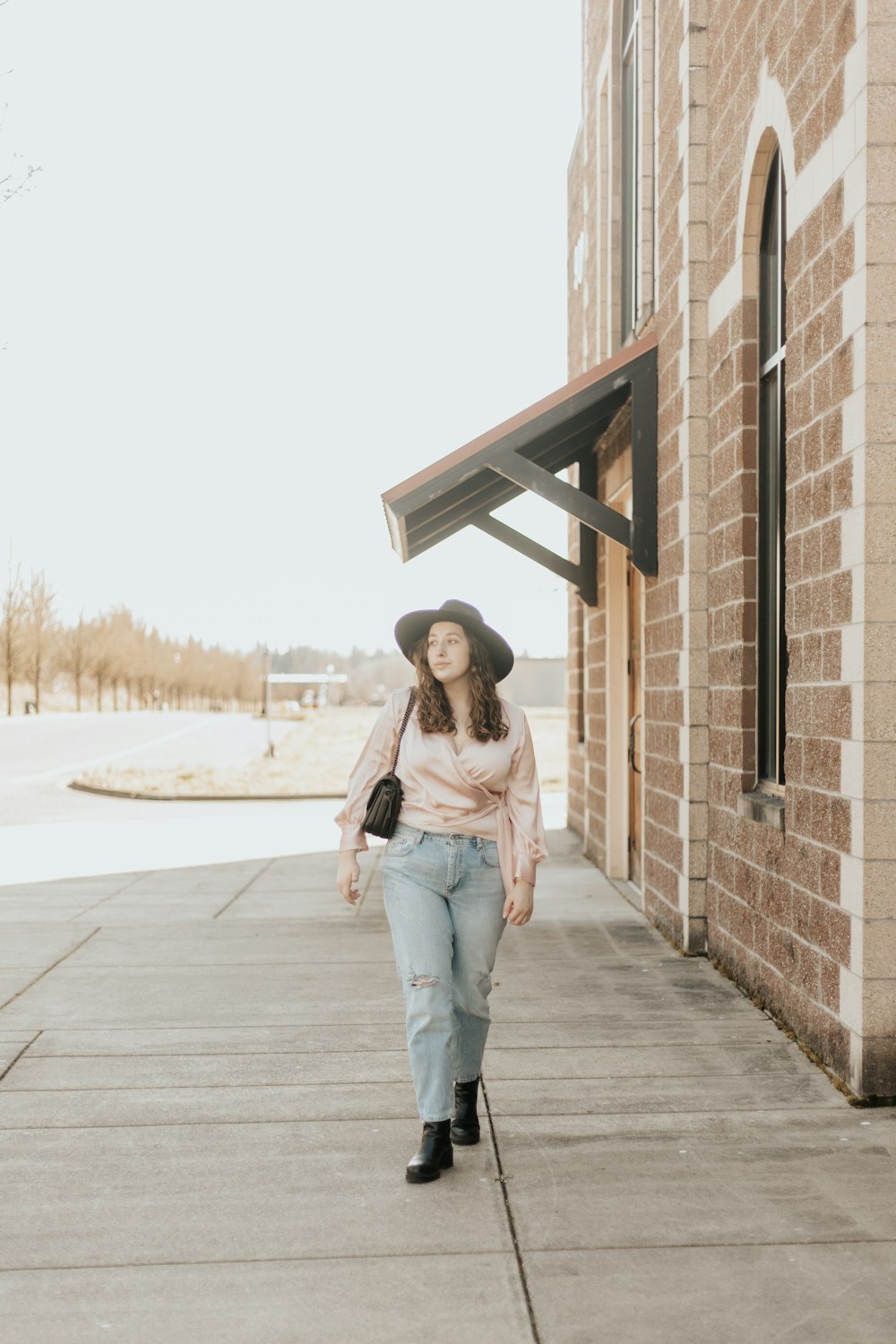 woman in blue denim jeans standing on brown brick wall during daytime