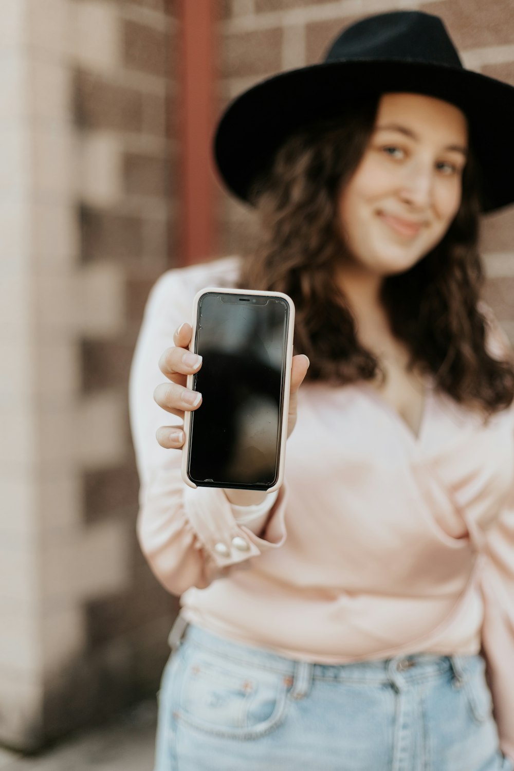 woman in white long sleeve shirt holding black smartphone