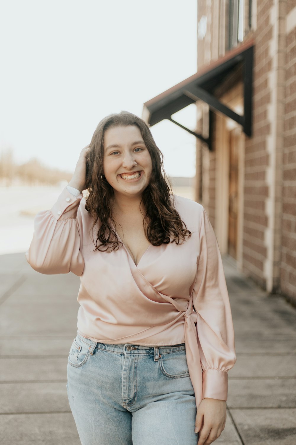 mulher na camisa rosa de manga comprida e shorts jeans azuis sorrindo