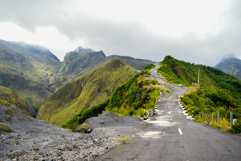 Route goudronnée grise entre des montagnes vertes pendant la journée