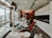 A modern dental clinic interior with dental chairs lined up near large windows, bright overhead lighting, and cabinetry. The room is well-organized and appears clean and professional, with a neutral color scheme and urban city view through the windows.