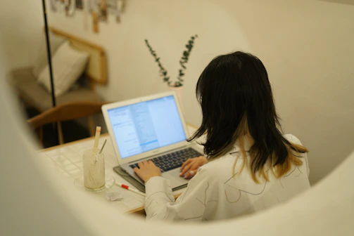 woman in white long sleeve shirt using laptop computer