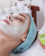 woman lying on blue towel with white cream on face