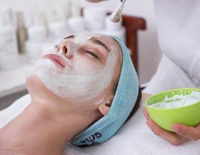 woman lying on blue towel with white cream on face