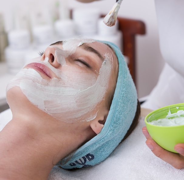 woman lying on blue towel with white cream on face