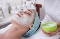woman lying on blue towel with white cream on face