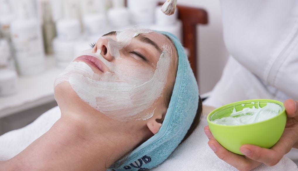 woman lying on blue towel with white cream on face