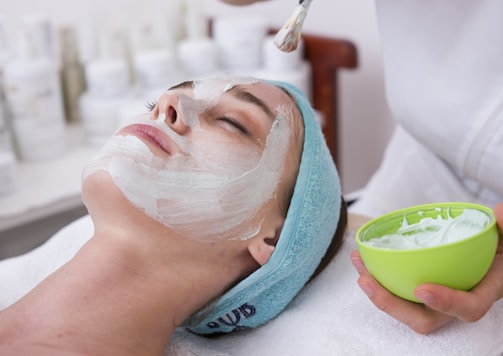 woman lying on blue towel with white cream on face