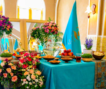 A lively cultural event with people sharing traditional Iranian and German dishes around a decorated table.