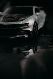 A sleek black car gleaming after a meticulous exterior wash and polish on a dark, moody backdrop.