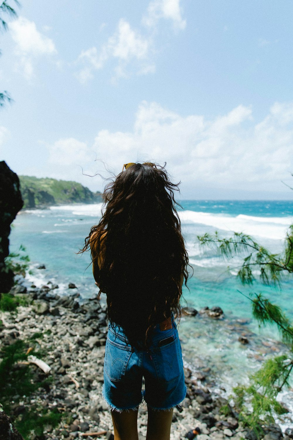 woman in blue denim jacket standing on seashore during daytime