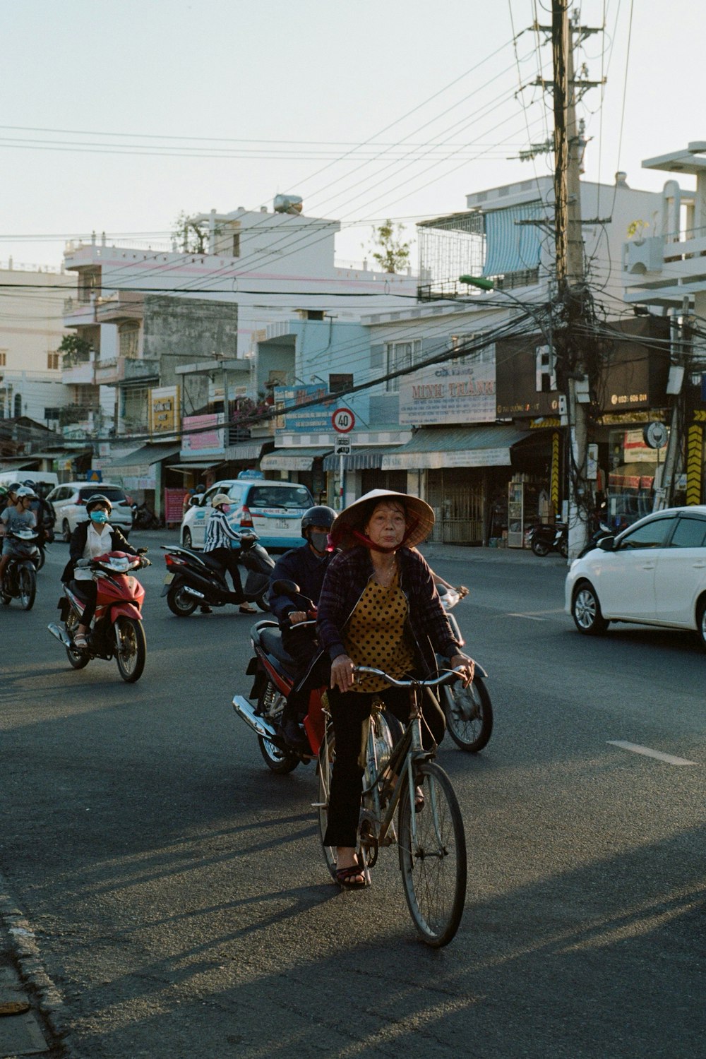 woman in brown and white dress riding on bicycle during daytime
