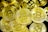 A pile of gold-colored coins with the Bitcoin symbol prominently displayed on each. The coins, with intricate detailing, overlap each other creating a dense, textured surface.