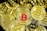 A collection of cryptocurrency coins with the Bitcoin symbol prominently displayed, most of which are gold, except for one coin in the center that features a red Bitcoin symbol.