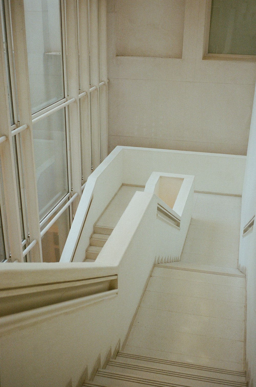 Escalera de madera blanca cerca de ventana de vidrio con marco de madera blanca