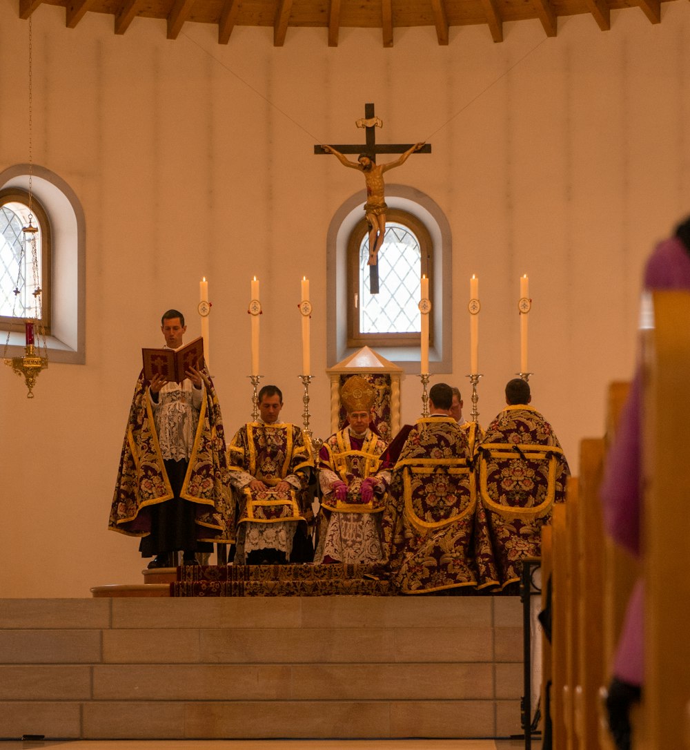 people in gold and black traditional dress standing on white wooden bench