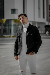Stylish black streetwear jacket with sharp tailoring and clean lines, displayed on a model walking city streets at dusk.
