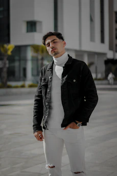 Stylish black streetwear jacket with sharp tailoring and clean lines, displayed on a model walking city streets at dusk.