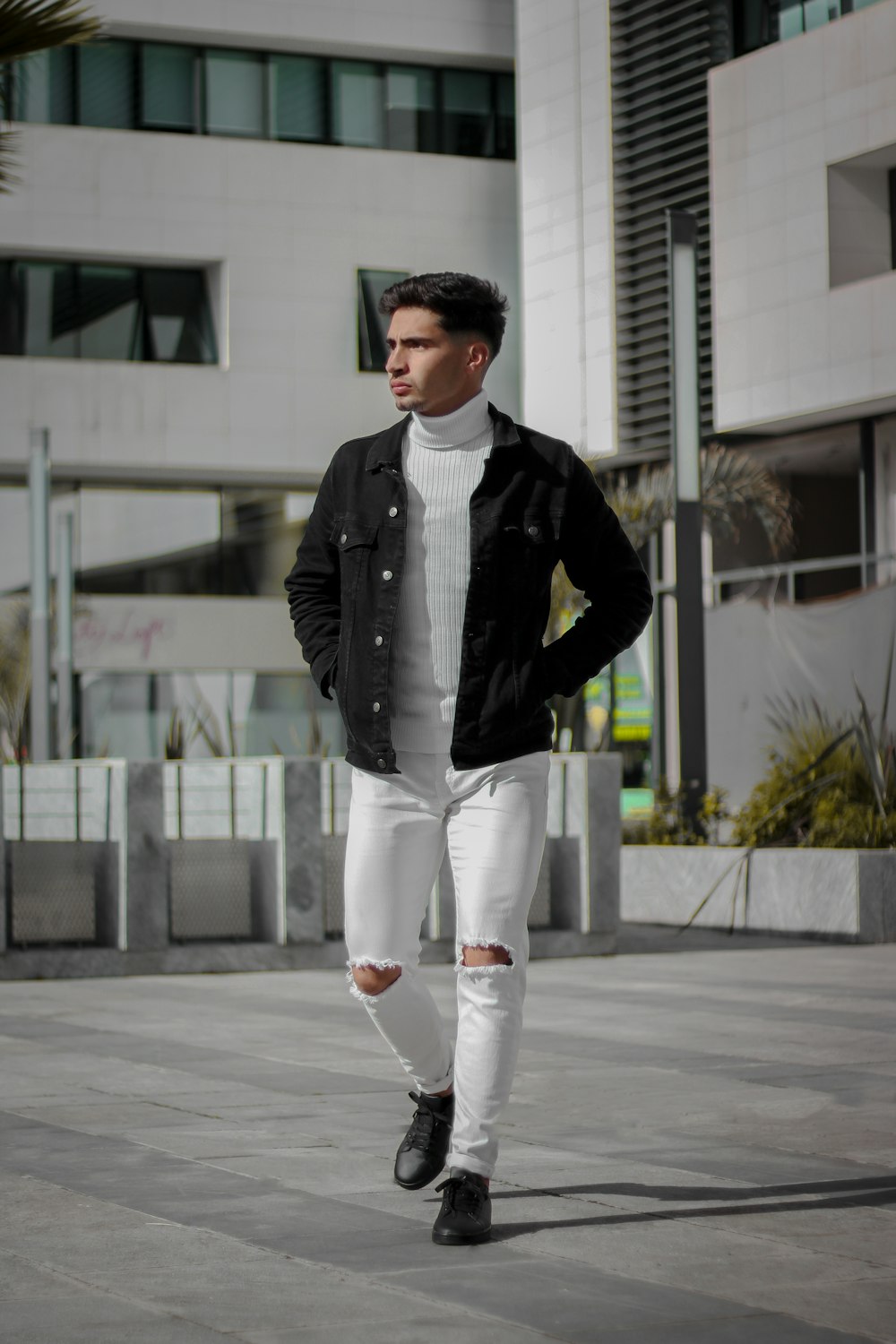 Foto hombre con chaqueta de cuero negro y pantalón blanco parado en el piso  de concreto gris durante el día – Imagen Marruecos gratis en Unsplash