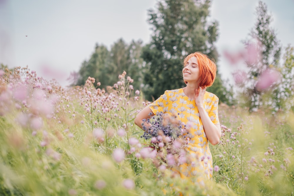 donna in abito floreale giallo e bianco in piedi sul campo di erba verde durante il giorno