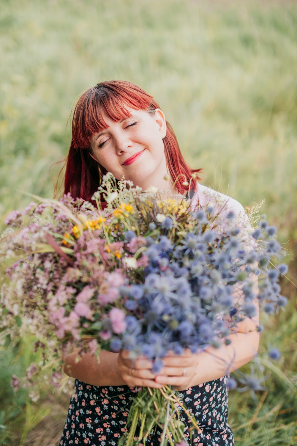 woman in white floral dress holding blue flowers