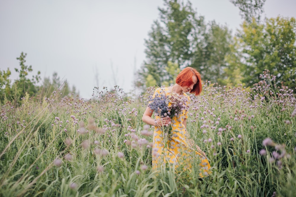 mulher no vestido floral amarelo e branco que está em pé no campo verde da grama durante o dia