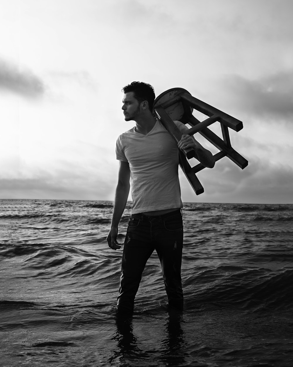 man in white t-shirt and black pants standing on beach