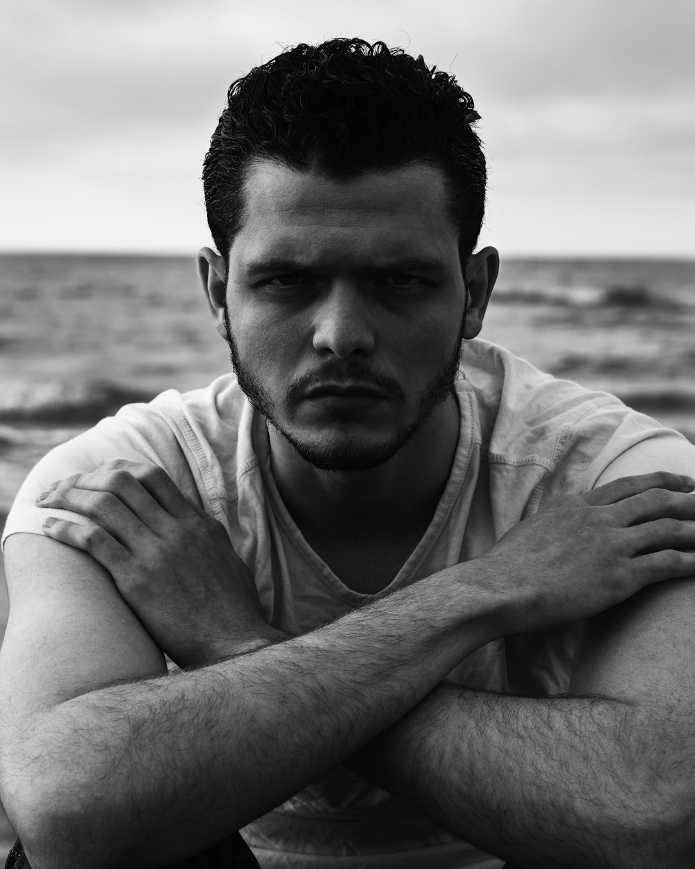 man in white crew neck t-shirt sitting on beach during daytime