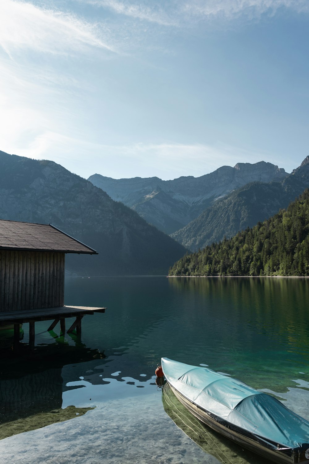 brown wooden house on lake near mountains during daytime