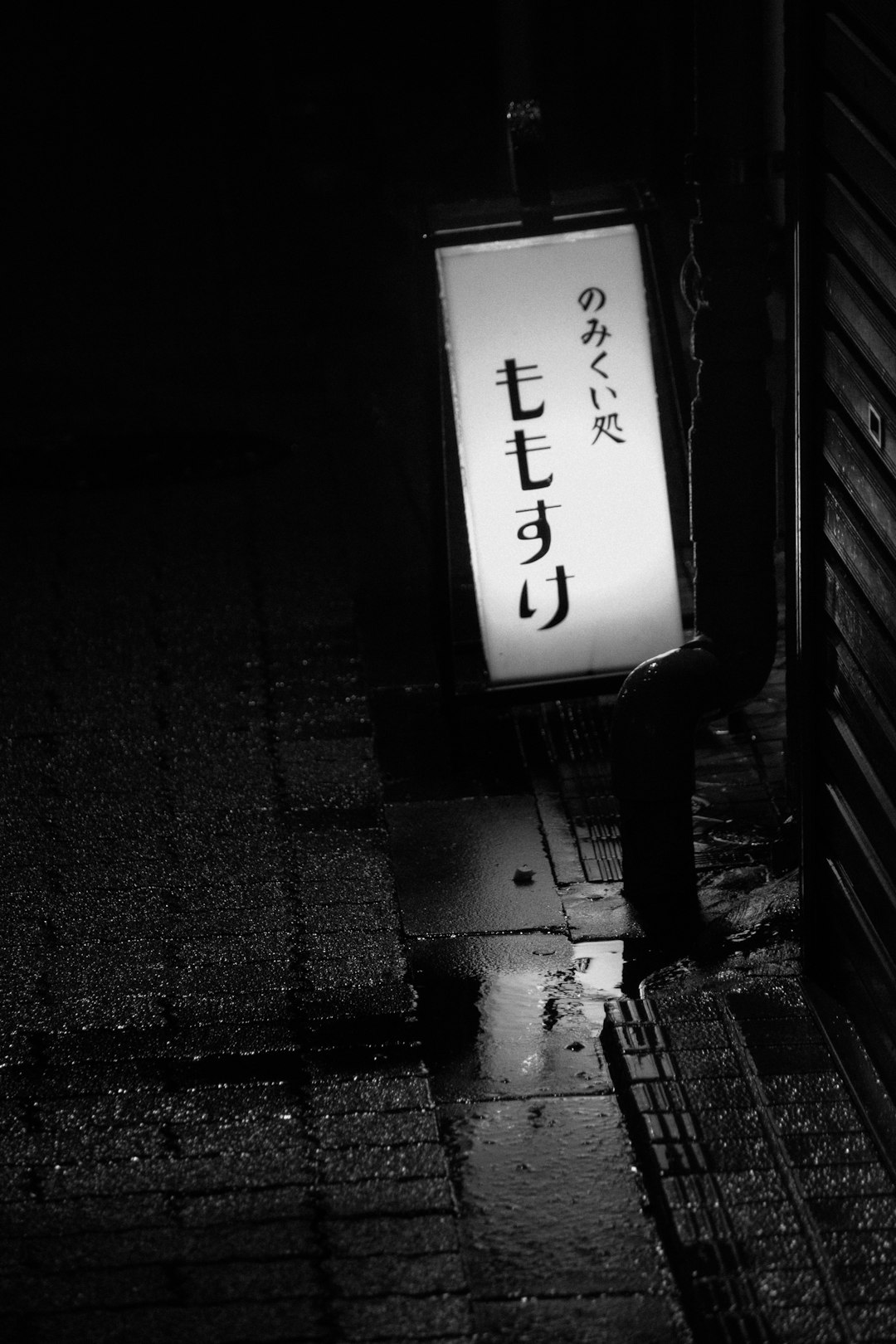 grayscale photo of man walking on sidewalk