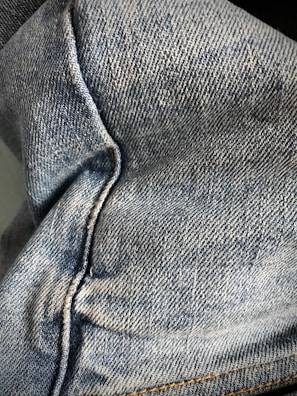 Detail shot of denim jeans highlighting the stitching and fabric texture.
