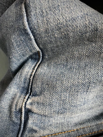 Close-up of denim fabric texture with detailed stitching on a pair of women's jeans.