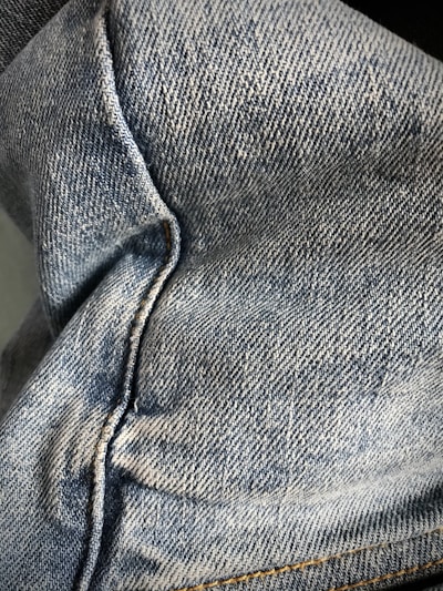 Close-up of denim fabric texture with visible stitching and rivets.