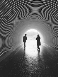 silhouette of man and woman walking in tunnel