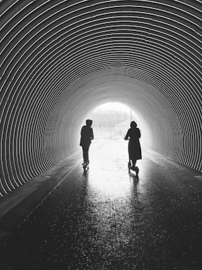 silhouette of man and woman walking in tunnel