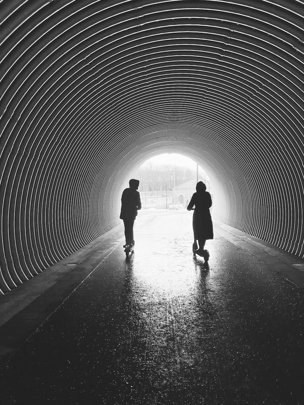 silhouette of man and woman walking in tunnel