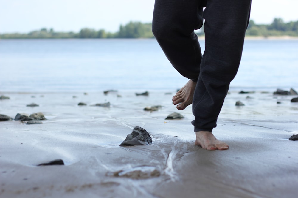 person in black pants standing on white sand during daytime