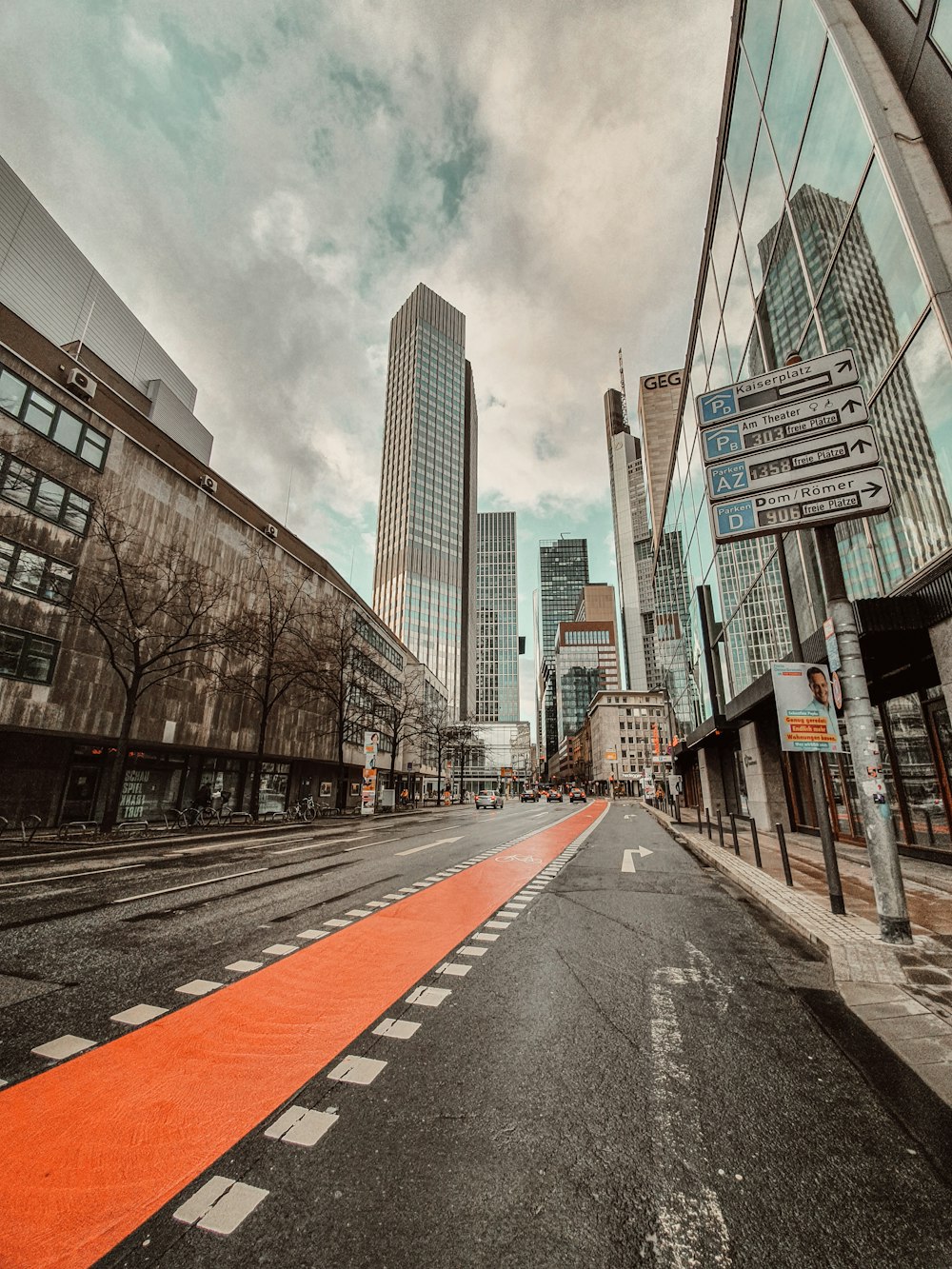 Graue Betonstraße zwischen Hochhäusern unter weißen Wolken tagsüber