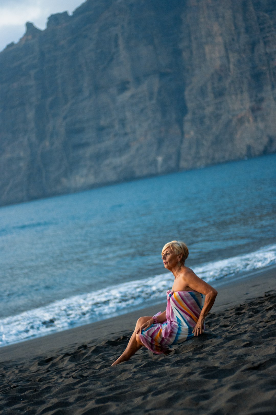 woman in purple and white dress sitting on beach shore during daytime