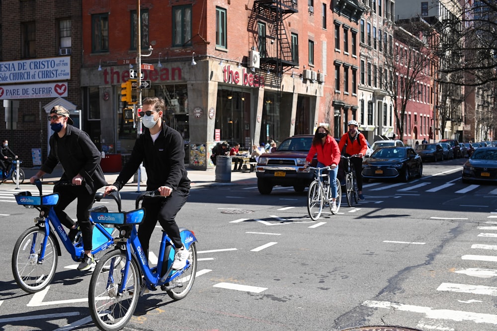 man in black jacket riding blue bicycle on street during daytime