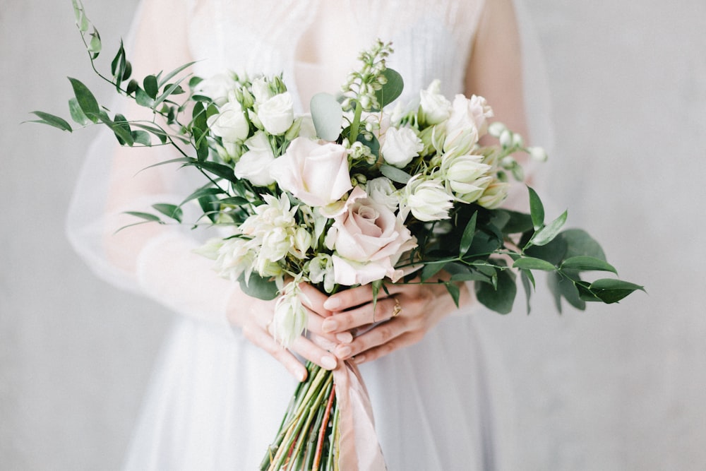 woman in white floral dress holding white rose bouquet