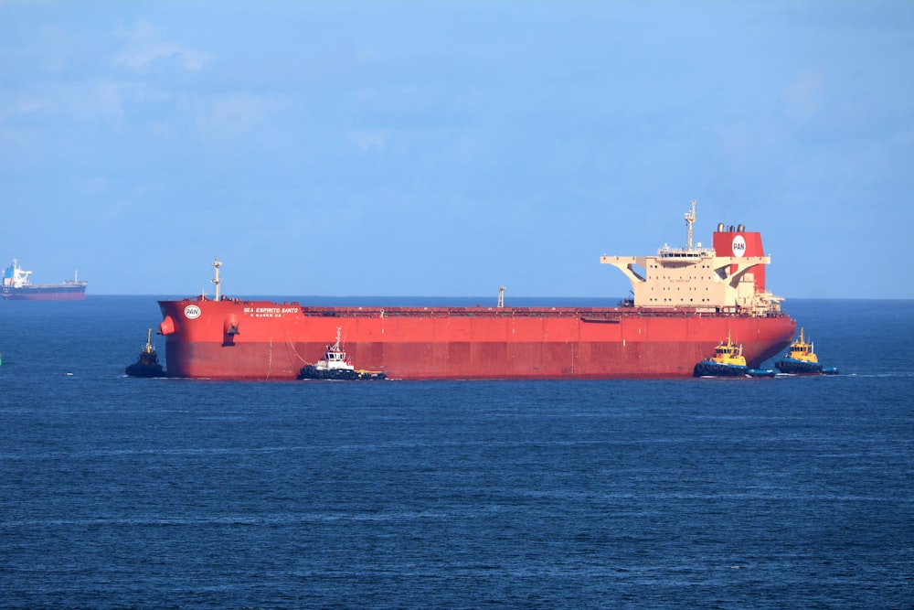 a large red cargo ship in the middle of the ocean