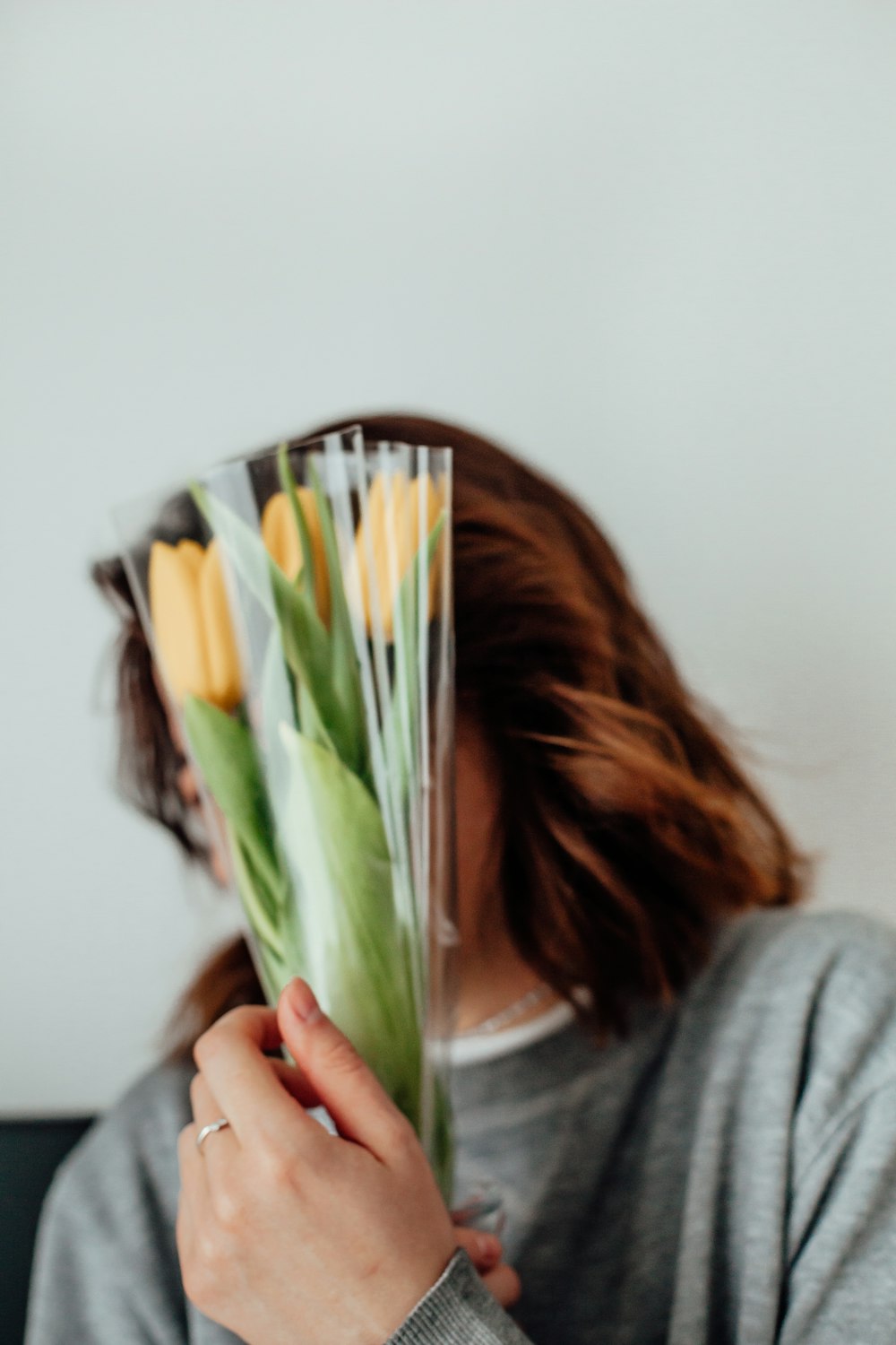 woman in gray long sleeve shirt holding yellow and green flower bouquet