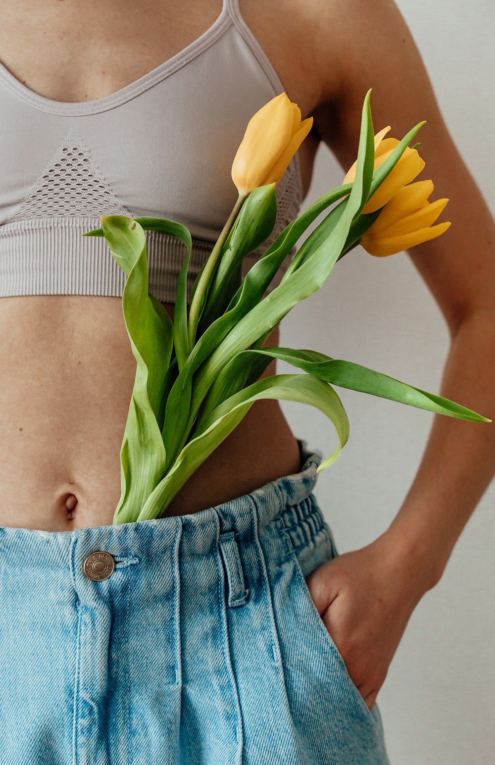 woman in blue denim shorts holding yellow flower
