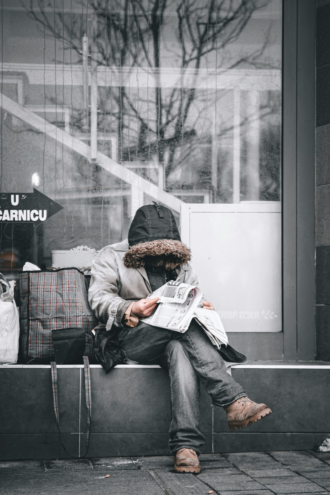 man in brown jacket reading newspaper