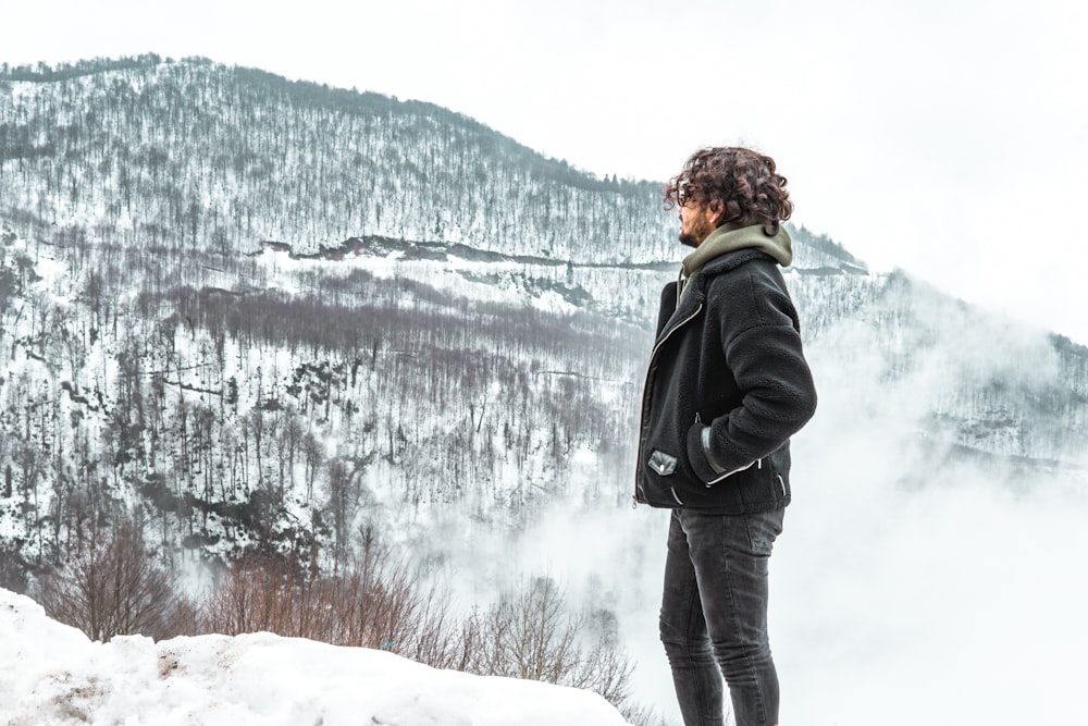 man in black jacket standing on snow covered ground