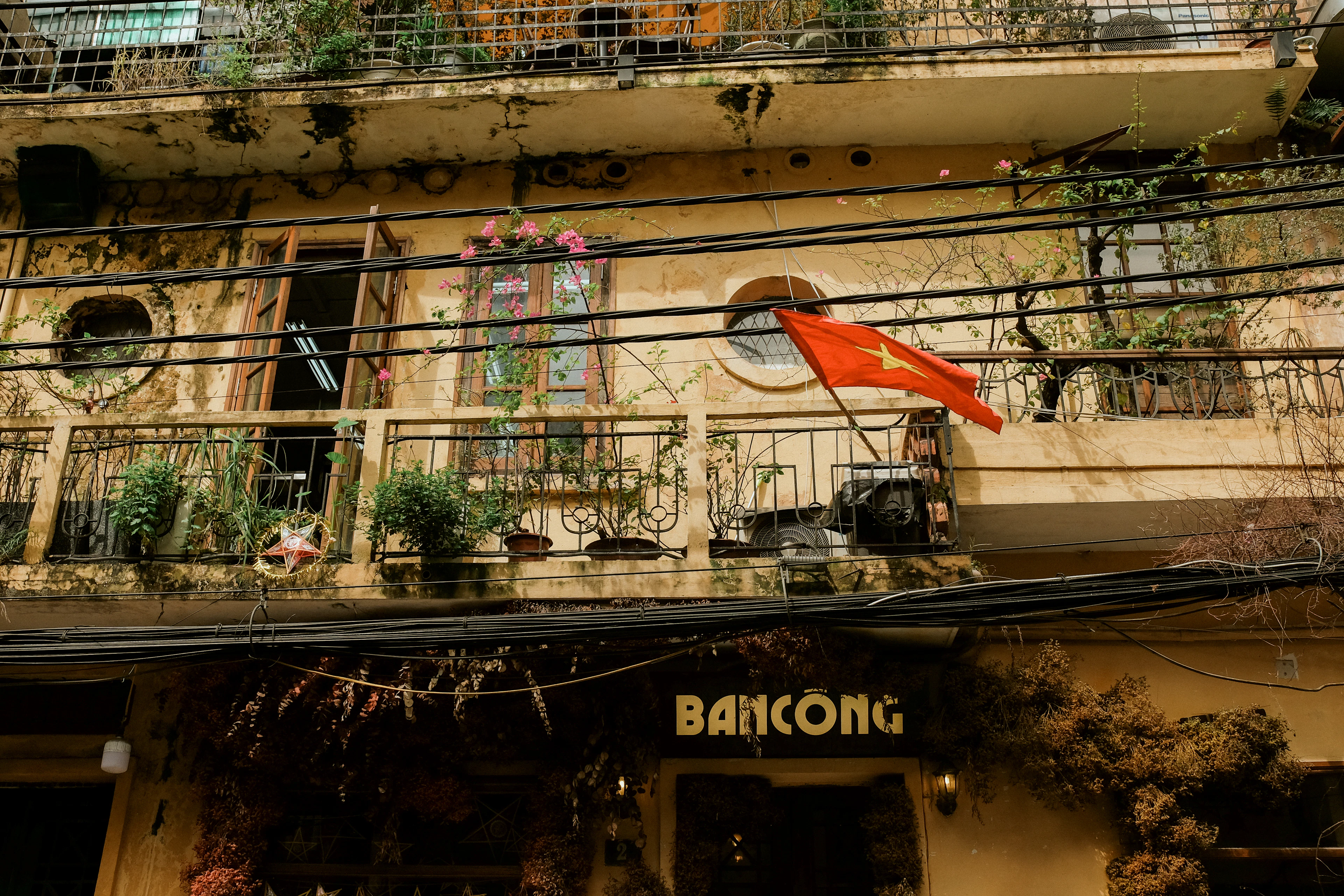 A balcony draped with a Vietnamese flag above a shopfront in Hanoi's Old Quarter