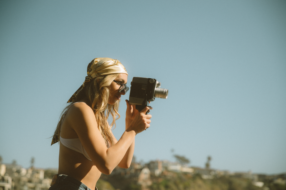 woman in black brassiere holding black dslr camera